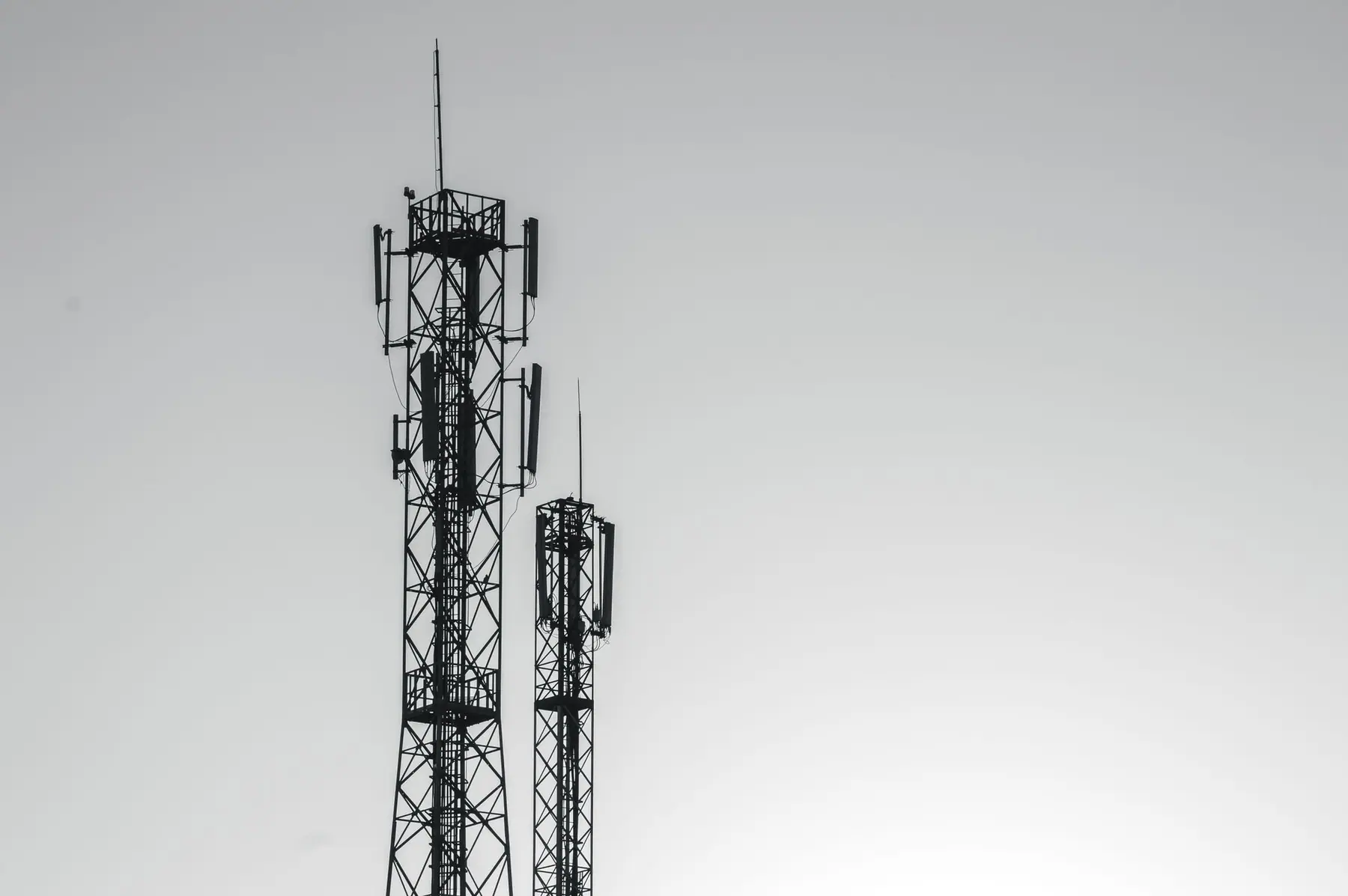 Deux pylônes d'antennes relais silhouettés sur un ciel pâle, à Rabat.