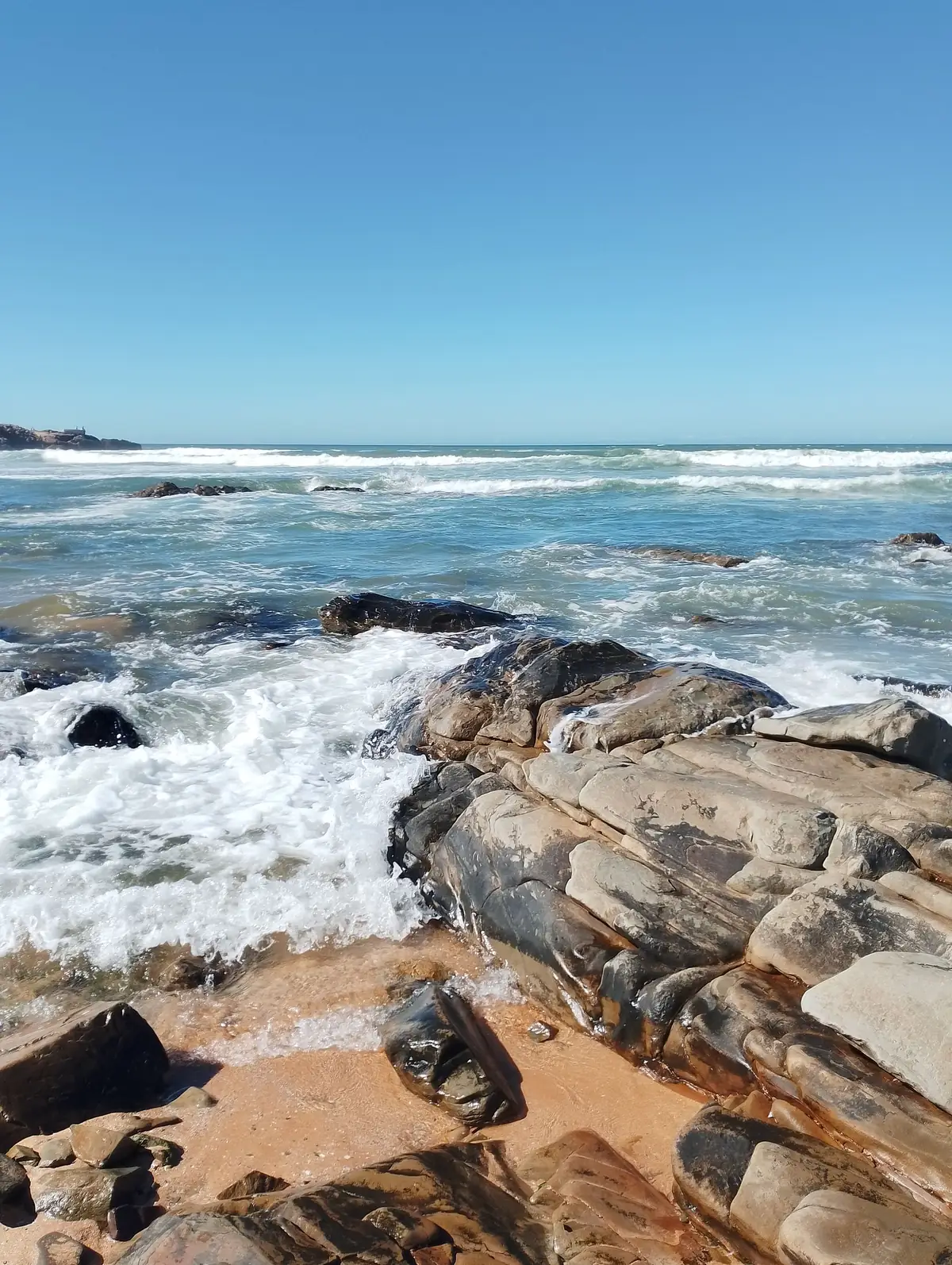 Côte rocheuse de Casablanca, vagues sur le sable et ligne d'horizon dégagée.